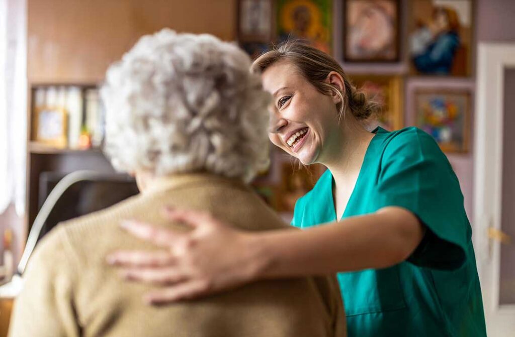 Two older adults sitting together in a cozy living room, talking and sharing a warm drink.