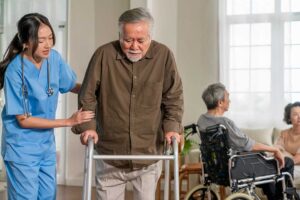 Older adults share a meal and conversation around a table in a bright assisted living dining room.